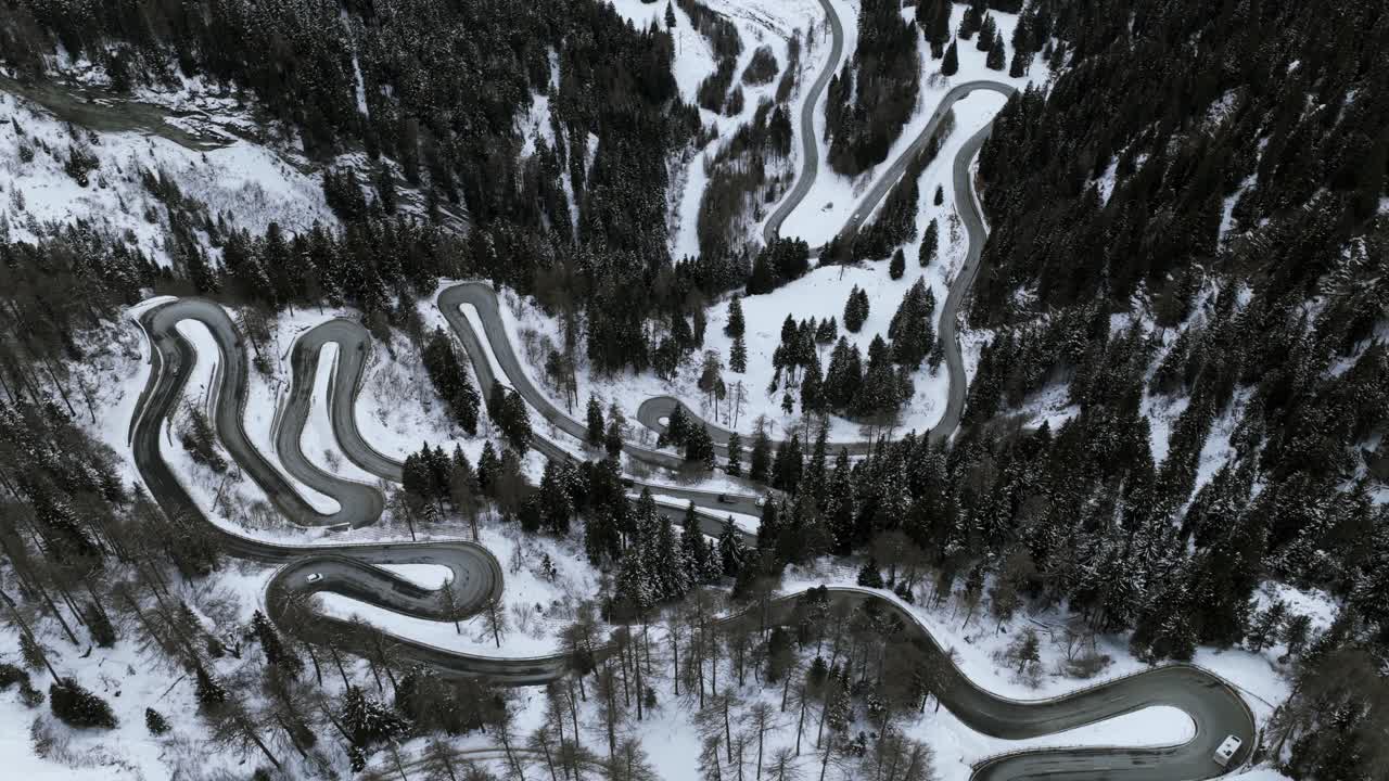 Aerial View of Winding Road Through Snow-Covered Maloja Pass in Switzerland During Winter Surrounded by Evergreen Trees and Mountain Landscape Travel Destination