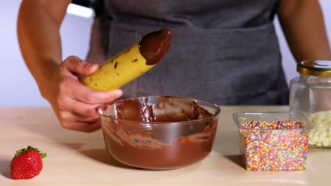 banana dipped in chocolate with sprinkles nearby