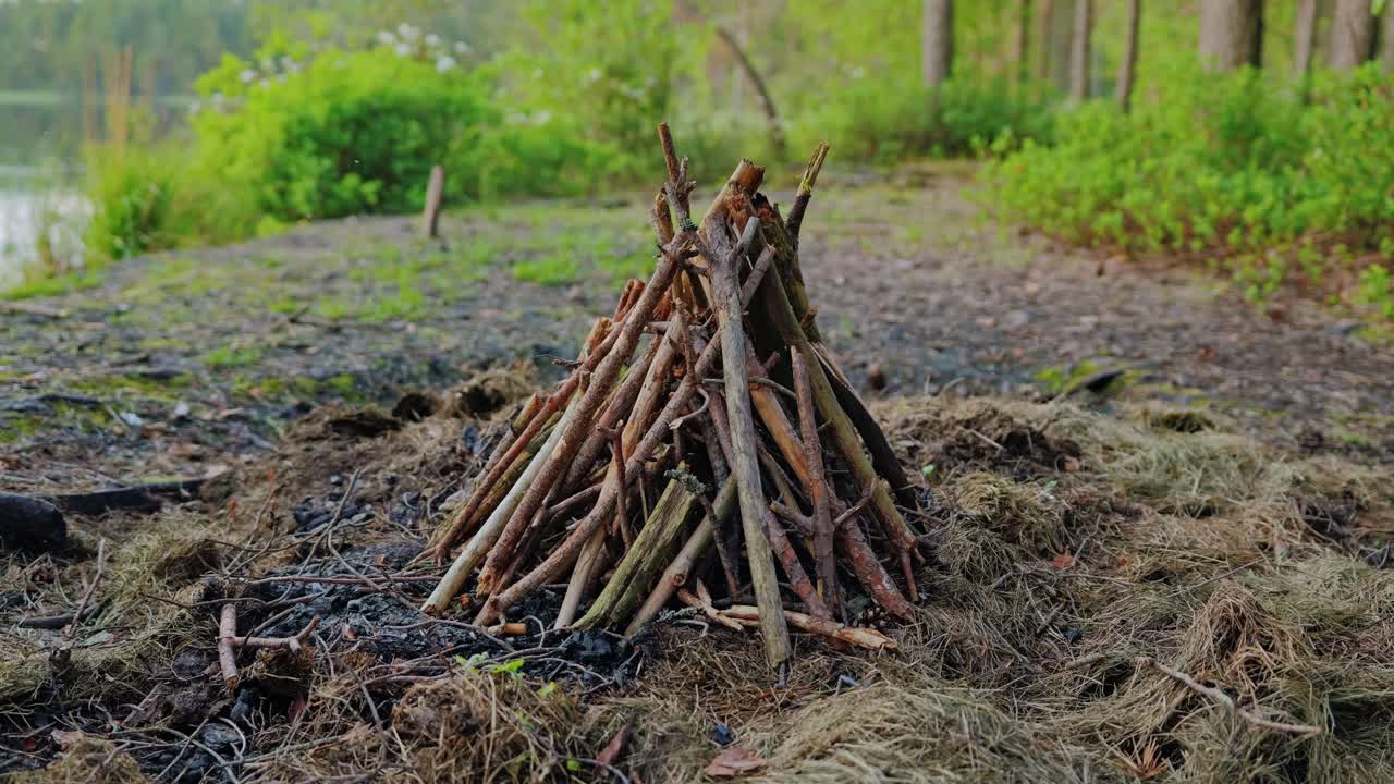 Dry sticks arranged in cone shape near swamp waters, zoom reveals stillness, 4K