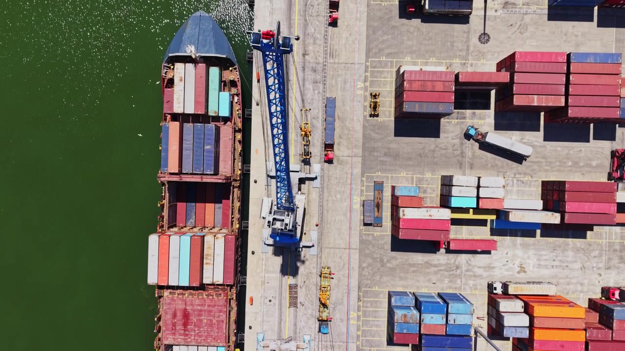 Container ship docked at port with crane and cargo area in view