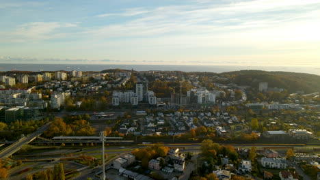 aerial trucking shot showing cityscape of gdynia during sunrise and blue baltic sea in backdrop - housing area district with high-rise building complex during sunny autumn day in poland,europe