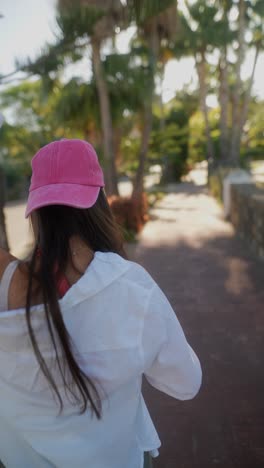 woman in a pink hat and white shirt in a tropical park