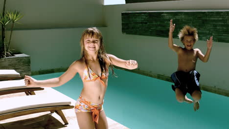 young girl dancing while brother jumping in the swimming pool