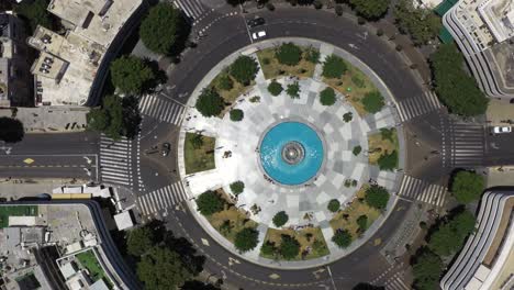 rotação aérea de cima para baixo da praça dizengoff em tel aviv, israel, mostrando tráfego nas ruas, áreas verdes, áreas pavimentadas e uma fonte azul no centro