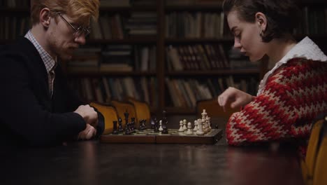 couple playing chess in a library