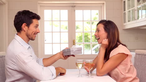 Happy-man-giving-his-partner-a-present-at-the-table