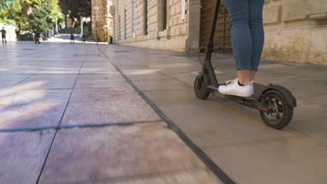 cerca de una mujer irreconocible montando scooter eléctrico en la ciudad