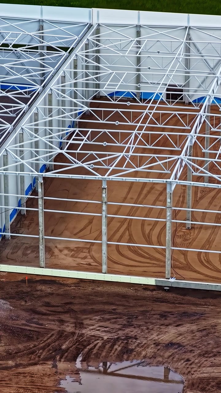 Intelaiatura in acciaio e struttura di supporto che si innalzano in un cantiere industriale, panoramica aerea verticale ravvicinata.