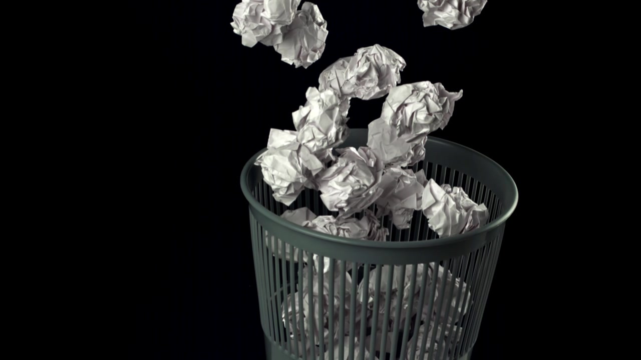 Palline di carta accartocciate che cadono in un cestino al rallentatore