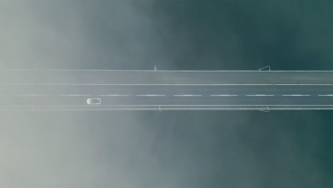 Weißes-Auto-Fährt-über-Brücke,-Vogelperspektive-über-Wolken