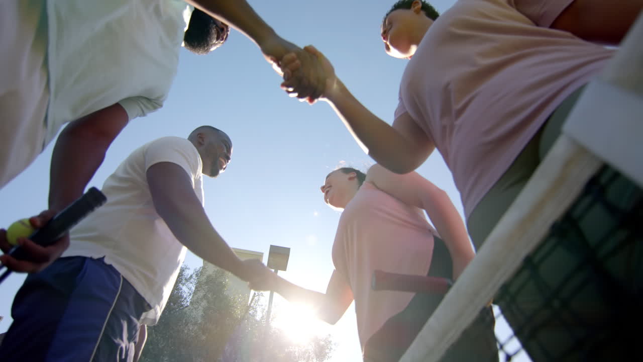 Shaking hands, Diverse Friends meeting on tennis court, holding rackets, enjoying sunny day