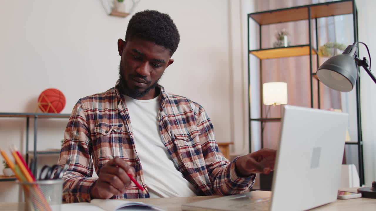 Young man guy using laptop computer sitting at table working, online shopping from home office