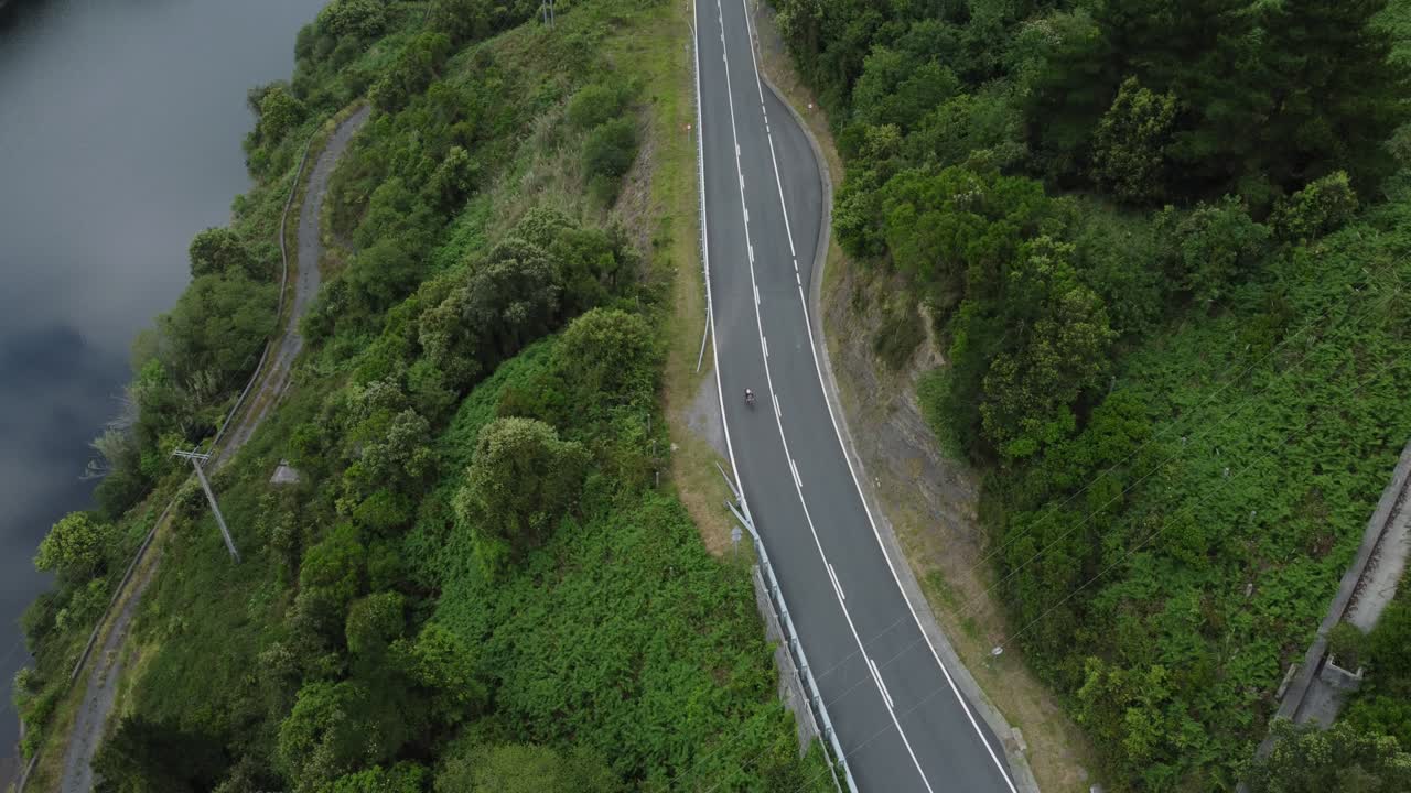 carretera de montaña curva y lago en un soleado día de primavera con un dron desde una vista aérea