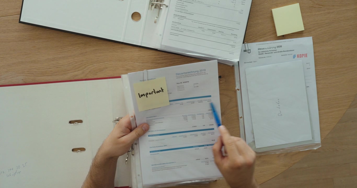 Organizing documents in a binder with an important sticky note. Ideal for office organization, paperwork, filing, and document management concepts.