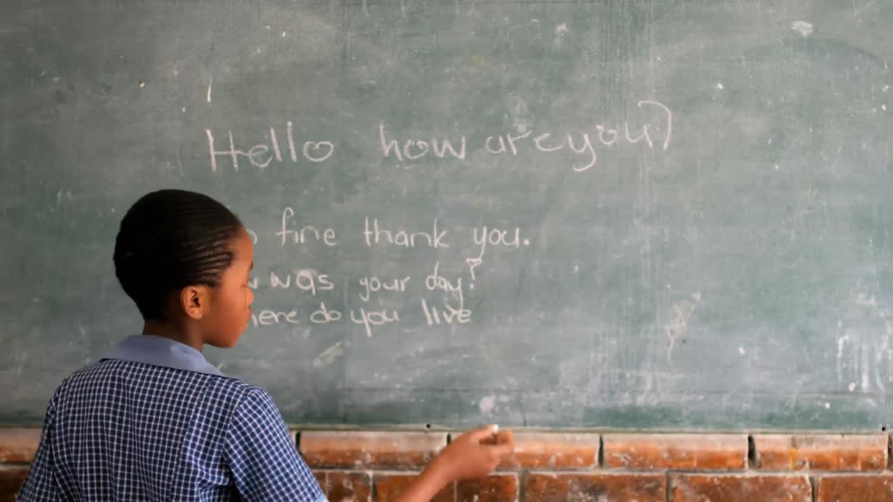 Schoolgirl writing on chalkboard in classroom 4k