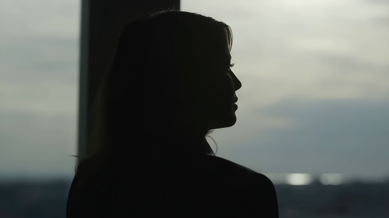 Silhouette di una donna che guarda fuori da una finestra