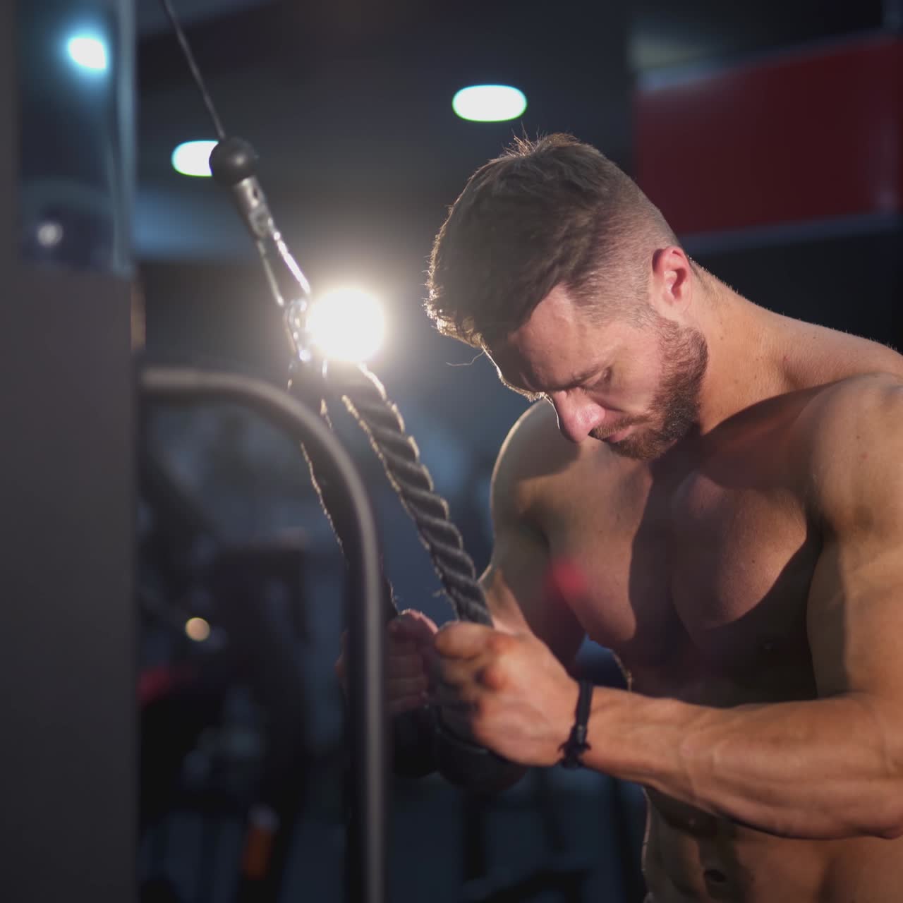Fisiculturista atraente com o torso nu se esforçando na academia. Homem musculoso se exercitando