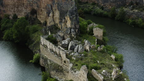 ruins of convent of our lady of the angels de la hoz on rocky cliff by the river in sebulcor, segovia, spain