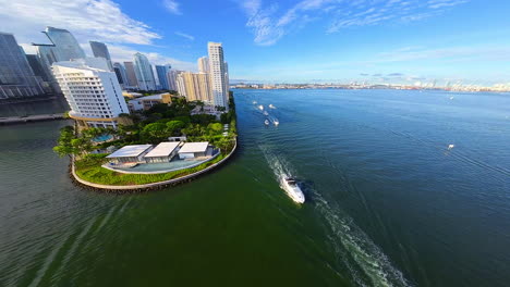 approaching beautiful green area at the waterfront of waterscape in american city. a few boats sail one by one. fpv drone footage.