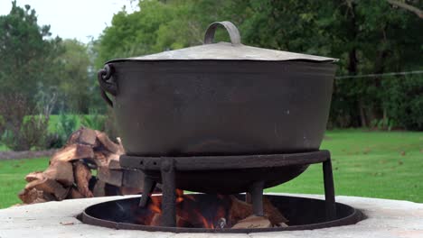 an old fashioned iron kettle over the fire of an outdoor campfire