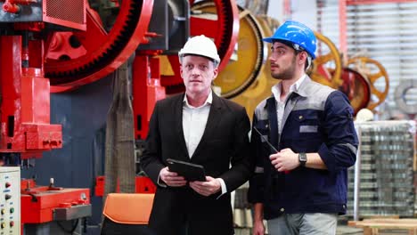 slow motion walking. lathe and stamping metal machine. business man and factory engineer in hard hat helmet talking and discussion at heavy industry manufacturing factory.