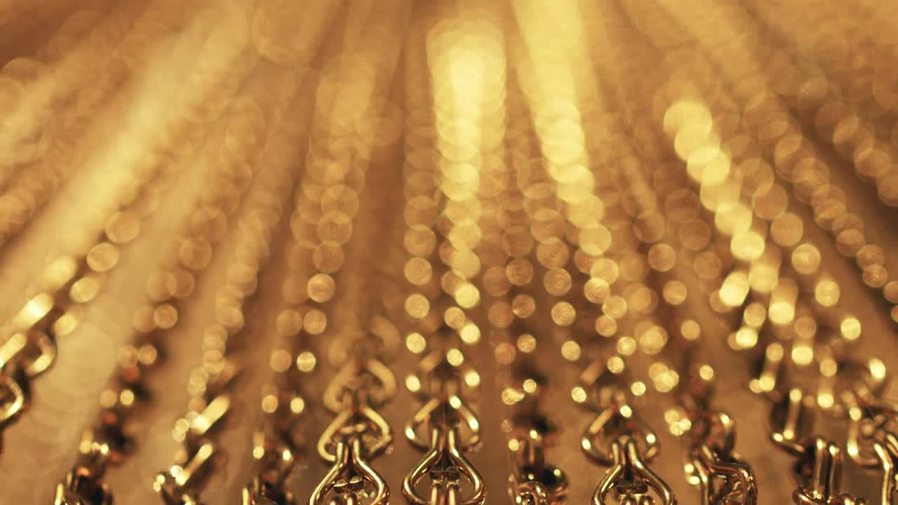 긴 금 사슬의 느리고 부드러운 움직임, 균일한 스, 휴식을 위한 금색 배경, 명상, 휴식, 진정시키기 위한 질감, 반이는 빛, 아래에서 위로 보이는 광경, 흐릿한 빛.