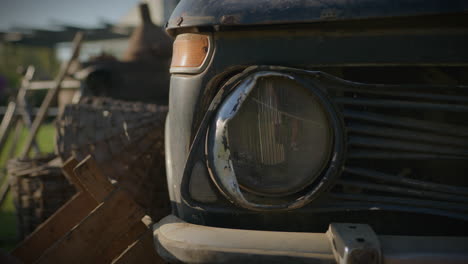 Coche-Viejo-Y-Oxidado-Faro-Dañado-Rodeado-De-Herramientas-Agrícolas-Rústicas