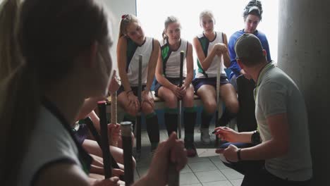 hockey coach talking with female players in locker room