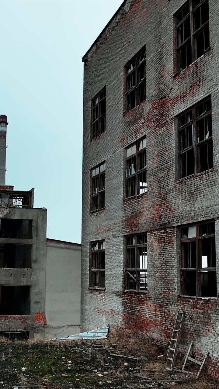 Industrial zone premises being ruined with time. Old buildings with broken windows ready to be demolished. Vertical video