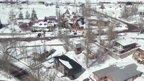 flyover in the snow-filled mountain village of farellones with clear streets and leafless trees on a sunny winter day