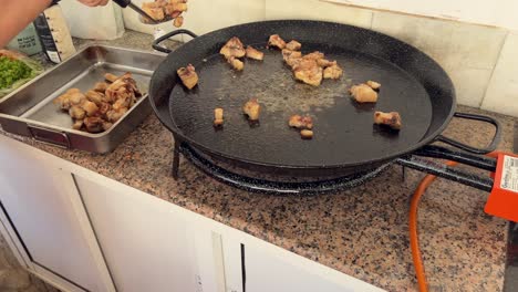 persona está fritando carne en un plato grande y quitándolos a otro cuenco de metal