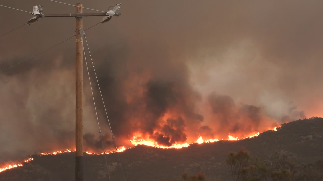 paisaje dramático de incendios forestales en la ladera, cielo oscuro debido a la velocidad del humo, casco