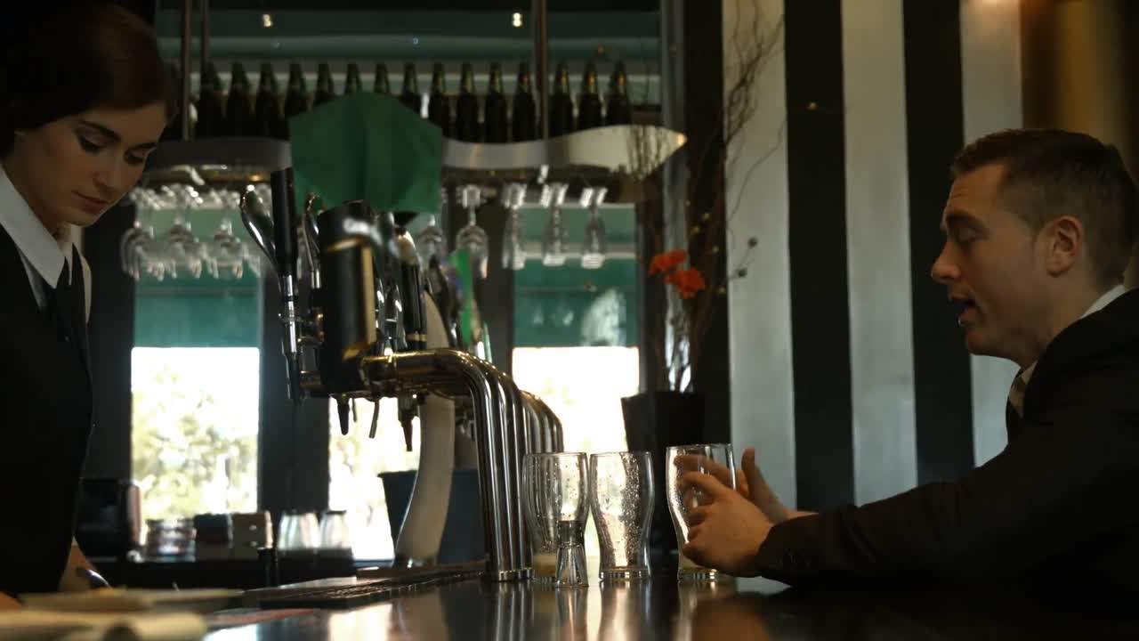 멋진 사업가가 카운터에서 맥주를 마시고 있습니다.