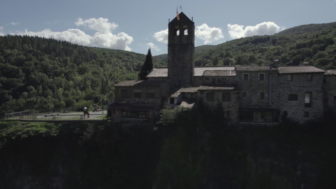 Drone's panoramic video showcases the breathtaking beauty of Castellfollit de la Roca, Spain: medieval village perched atop a striking volcanic cliff