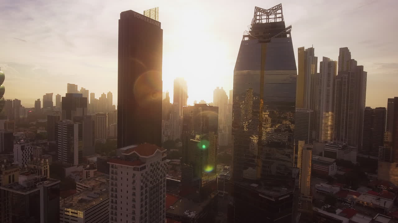 Imagem panorâmica de drone do horizonte da Cidade do Panamá ao pôr do sol, com reflexos do sol em edifícios altos.
