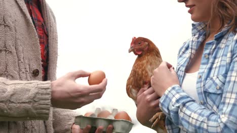 young couple holding hen and eggs