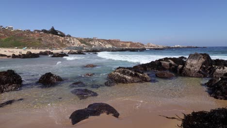 Welliger-Strand-Und-Häuser-Auf-Dem-Berggipfel-Am-Tunquen-Beach,-Chile