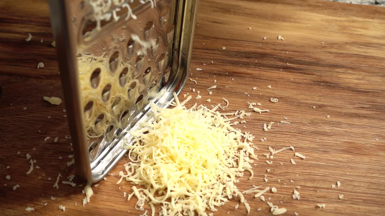 Il cuoco grattugia il formaggio su una grattugia. Rallentatore