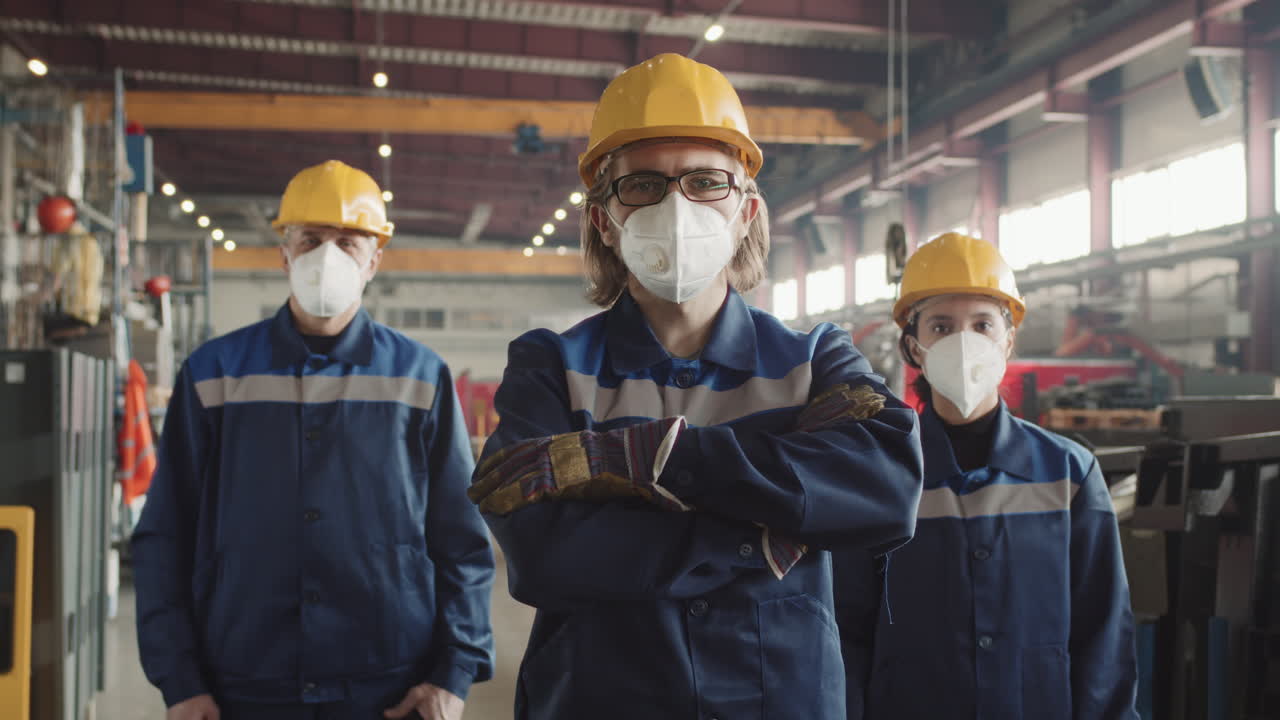 Trabajadores de fábrica con máscaras respiratorias posando para la cámara