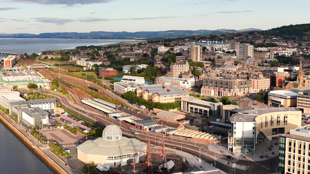 Drone camera smoothly pans over Dundee’s waterfront, urban landscape, modern architecture, and river