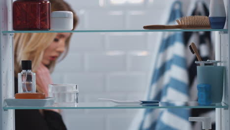 view through bathroom cabinet of anxious woman waiting for home pregnancy test result