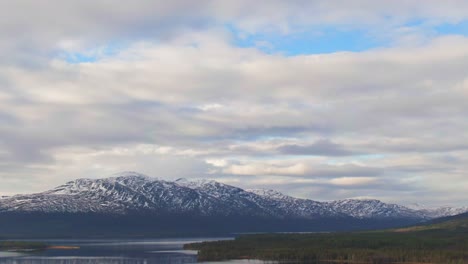 Swedish-Alpine-Forest-Lake-With-Snowcapped-Mountains-On-Cloudy-Day