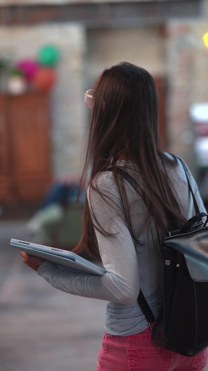 una adolescente caminando con una tableta