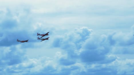 three red yak-50s aerobatic aircrafts carrying out dynamic maneuvers in front of spectators at baltic airshow in liepaja, latvia, white smoke trails, handheld shot