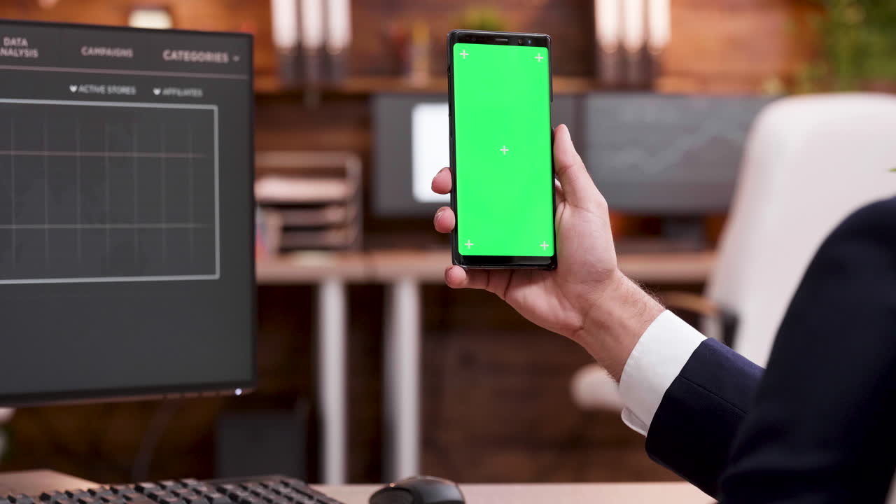 초록색 화면 을 가진 전화 를 들고 있는 사람
