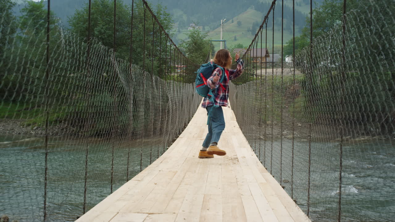 un turista emocionado corriendo por el puente del río. una mujer feliz saltando en las montañas.