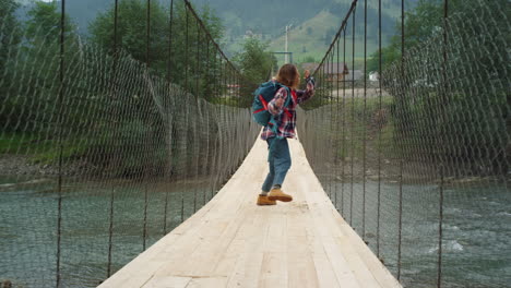 excited tourist hiker running on river bridge. happy woman jumping in mountains.