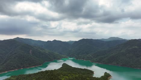 Vuelo-De-Drones-Sobre-El-Embalse-De-Feitsui-Con-Cordillera-Y-Agua-De-Color-Verde-En-Un-Día-Nublado---Colinas-Verdes-Cubiertas-De-Maleza-En-El-Desierto-De-Taiwán