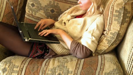 Attraktive-Frau,-Die-Einen-Laptop-Benutzt,-Der-Auf-Dem-Sofa-Sitzt