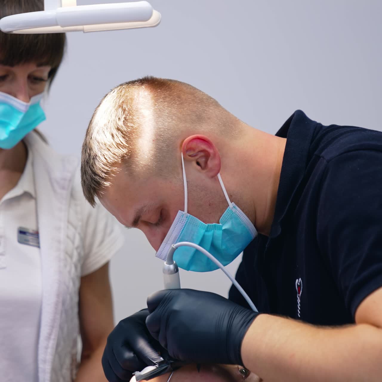Stomatologo che esegue una procedura dentale su un paziente. Dentista uomo e assistente con mascherine che curano i denti in un centro medico. Denti sani.